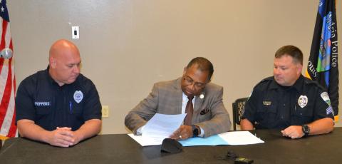 Mayor Jeffrey W. Hall (center) and representatives of Alexandria Police Officers Association Local 833 Bobby Branton (right) and Josh Peppers (left) formally sign the contract between the City and the union during a ceremony at the Public Safety Complex Wednesday, July 14. 